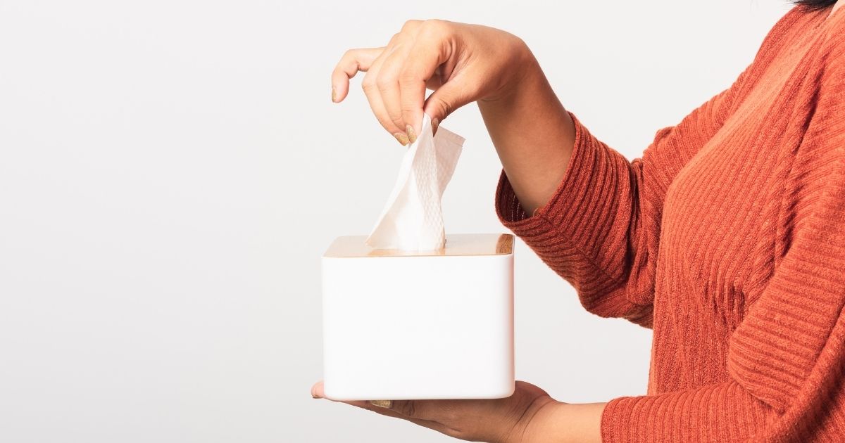 person's arm extended holding a box of tissues
