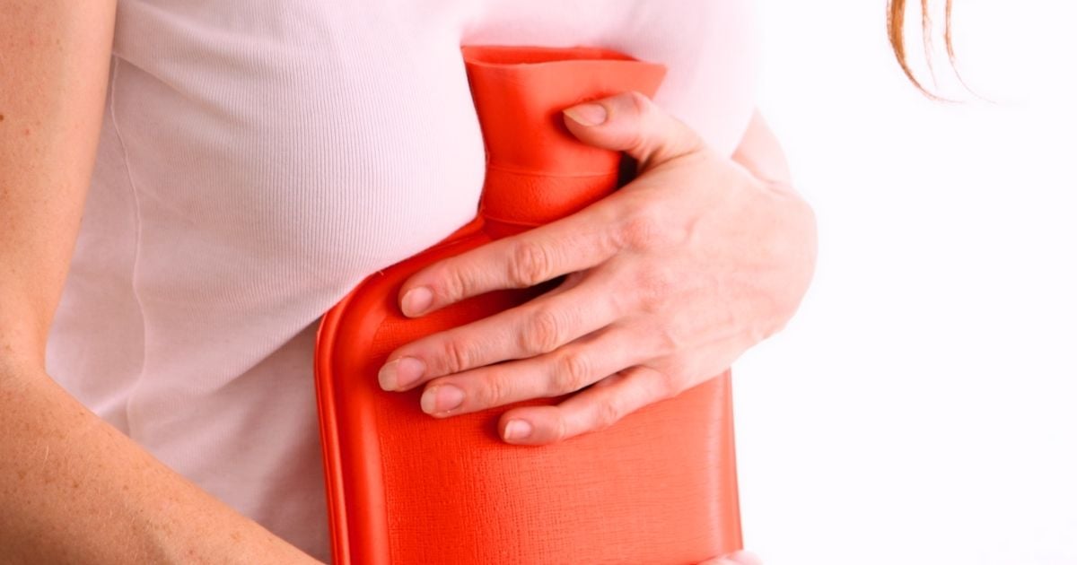 young woman hugging hot water bottle into tummy
