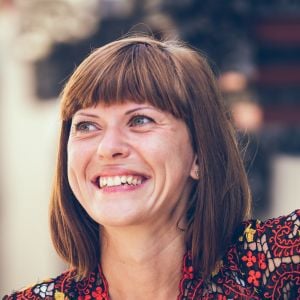 woman wearing patterned shirt straight fringe haircut outside smiling