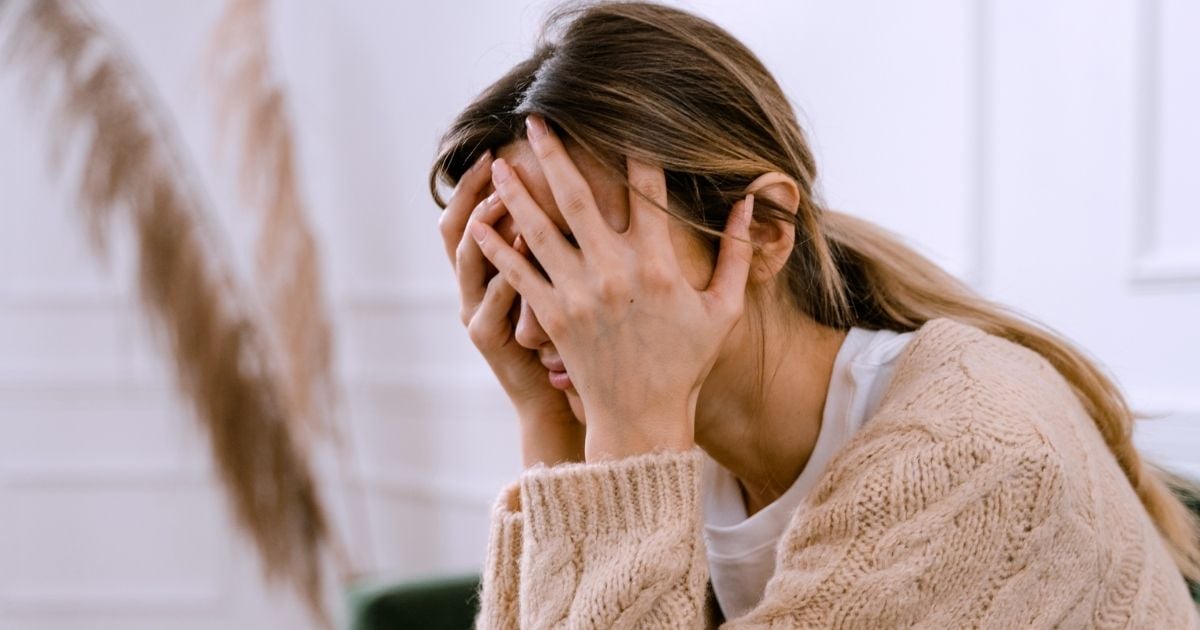 woman seated with head resting in hands covering face