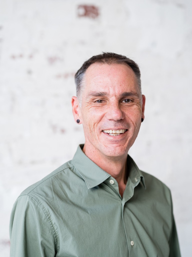 male functional medicine practitioner wearing green shirt standing smiling