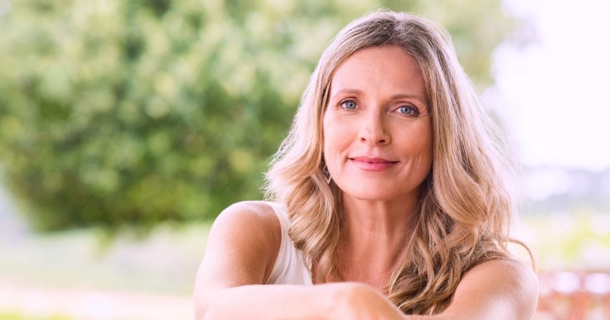 woman of menopausal age sitting outside with gentle smile