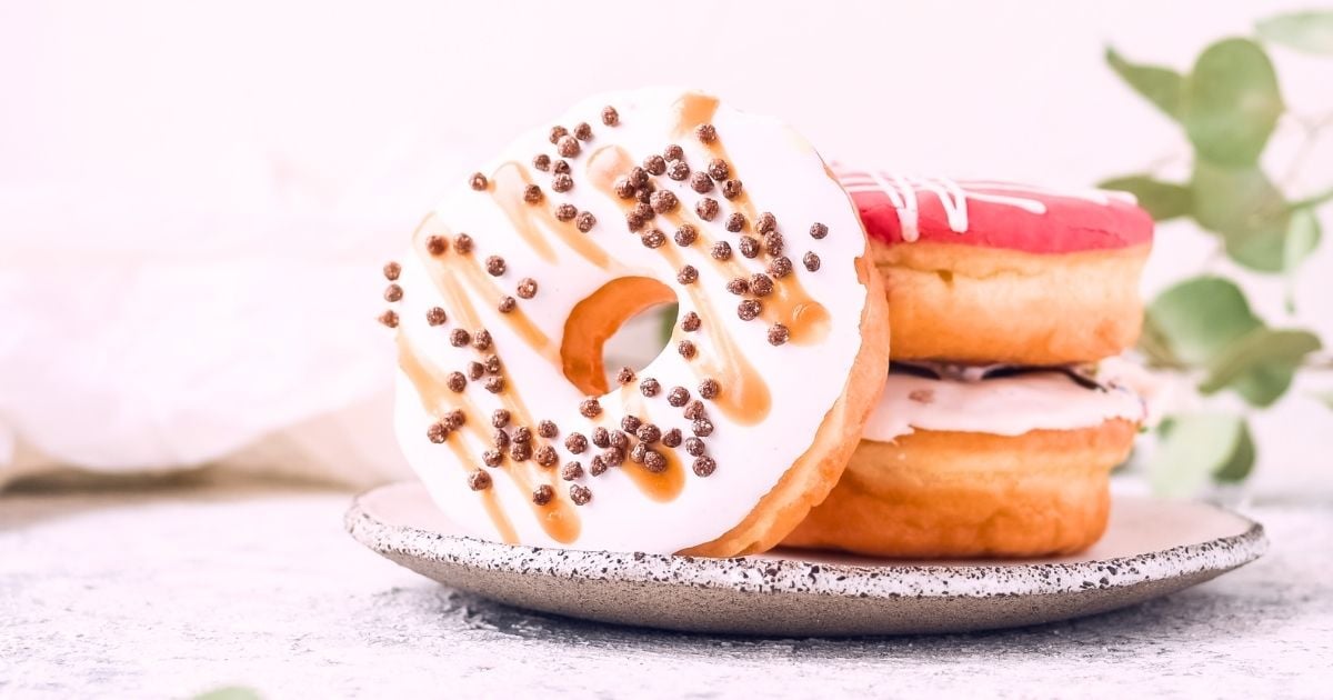 three iced donuts stacked on a rustic plate