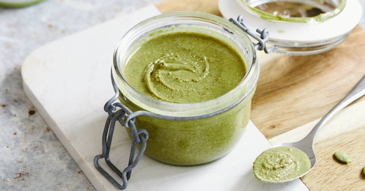 small jar of green pumpkin seed nut butter on wooden marble chopping board