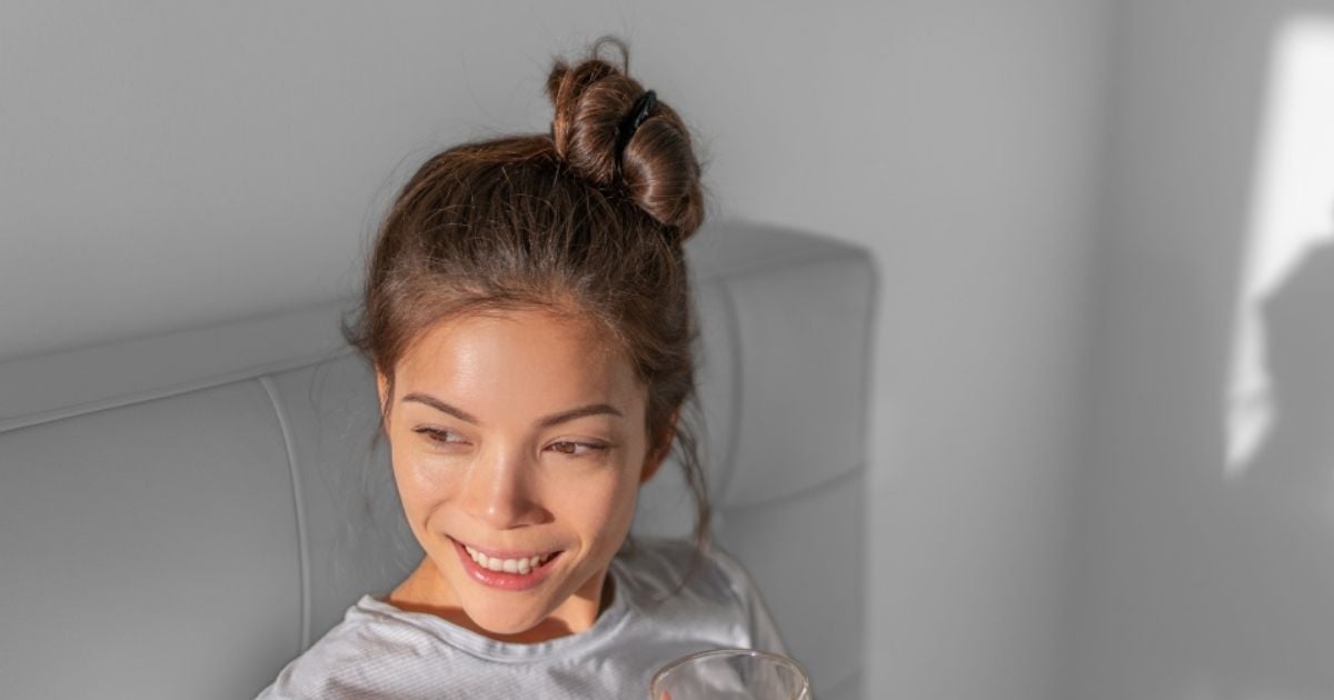 vibrant health young woman relaxing on couch with warm drink sun on face