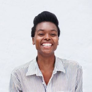 woman standing outside in front of white wall laughing
