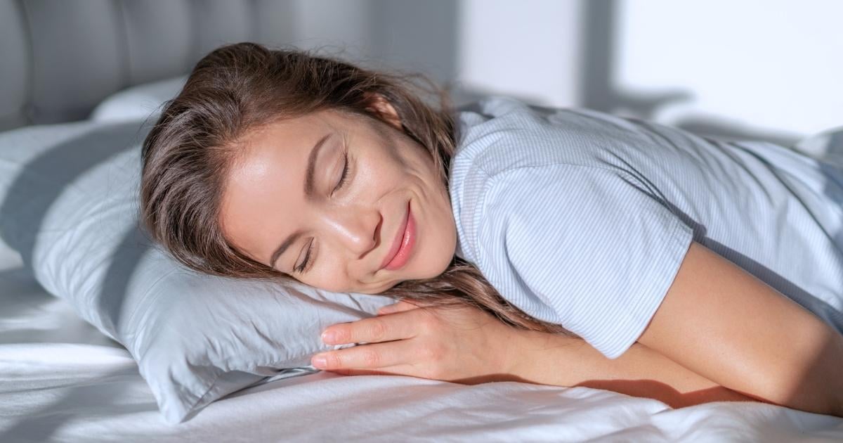 middle aged woman sleeping peacefully with gentle smile head rested on soft white pillow