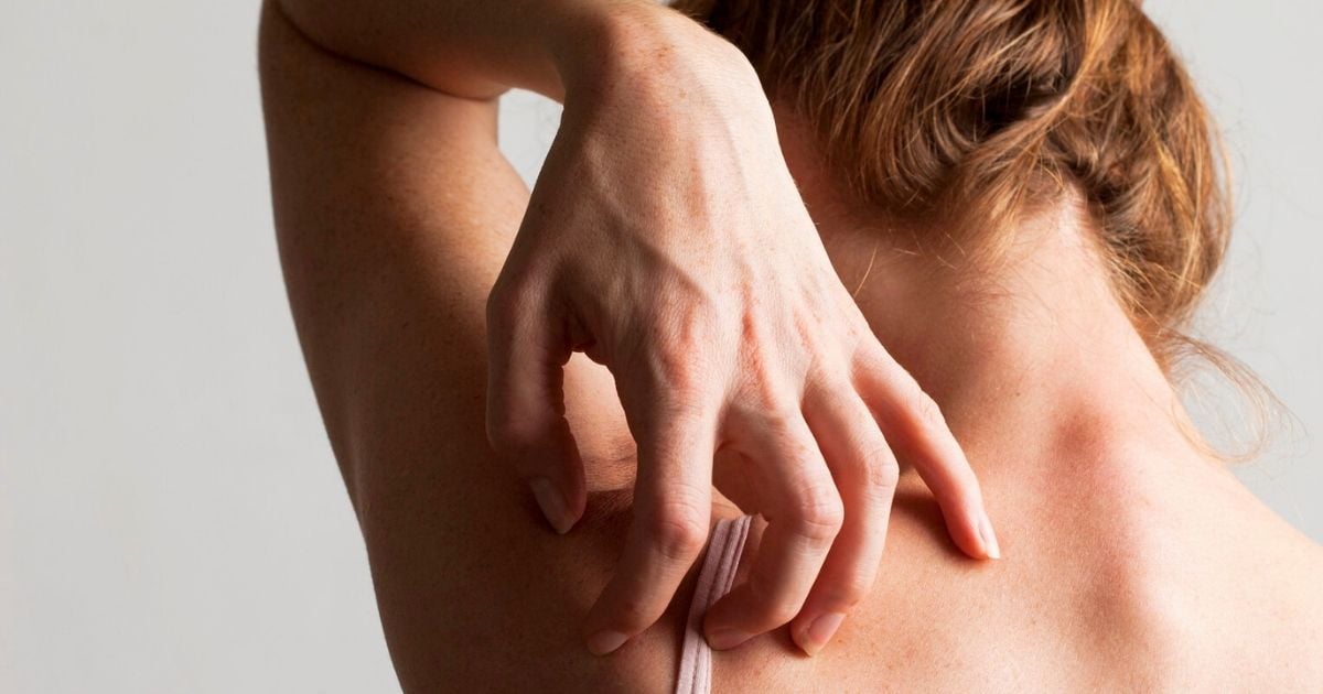 woman with hair in bun reaching over to sratch bare skin back